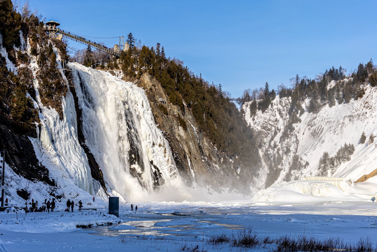 Frozen waterfall cascading down a snowy mountain under a blue sky, perfect for winter nature photography.