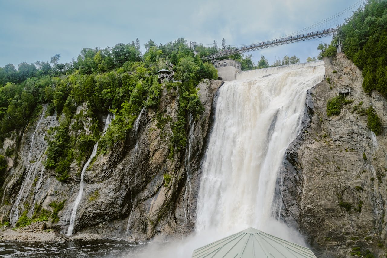 Majestic view of Montmorency Falls with lush greenery and a suspension bridge in Québec City.