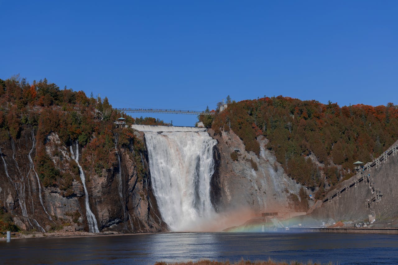 Breathtaking view of Montmorency Falls with autumn foliage under a clear blue sky.