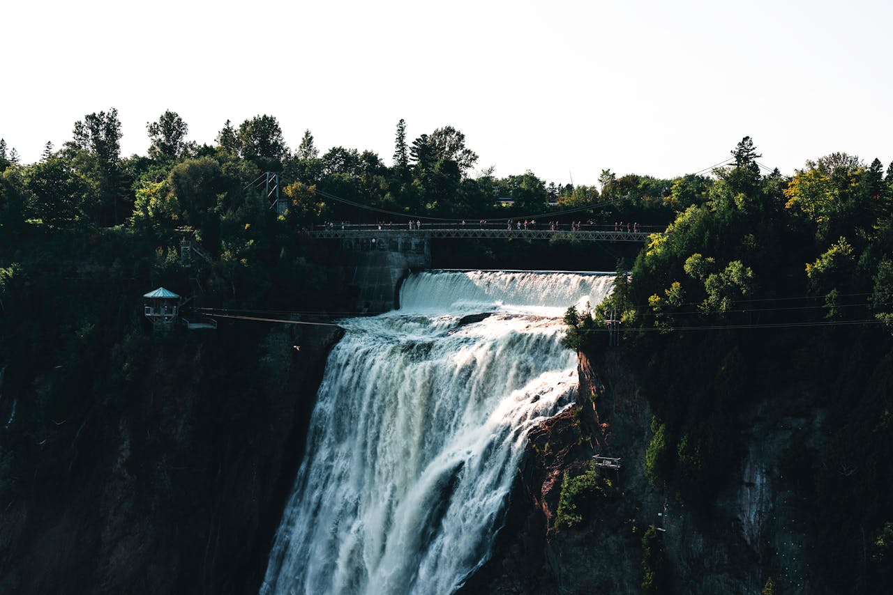 Stunning view of Montmorency Falls in Québec surrounded by lush greenery and a pedestrian bridge.