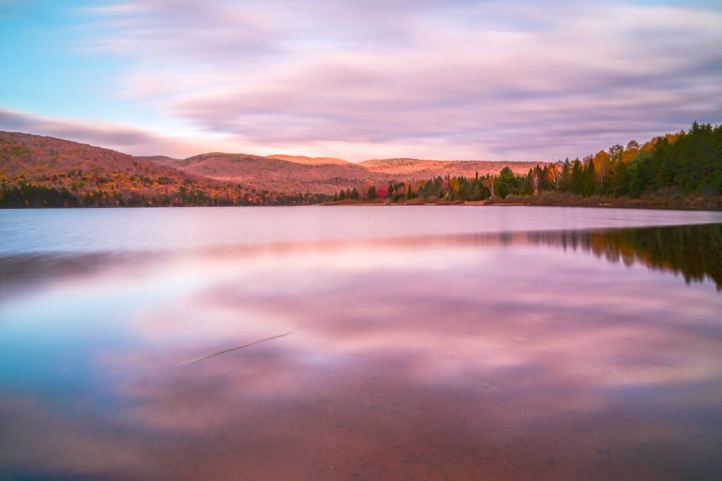 Breathtaking autumn view of Mont-Tremblant reflecting on a tranquil lake during sunrise.
